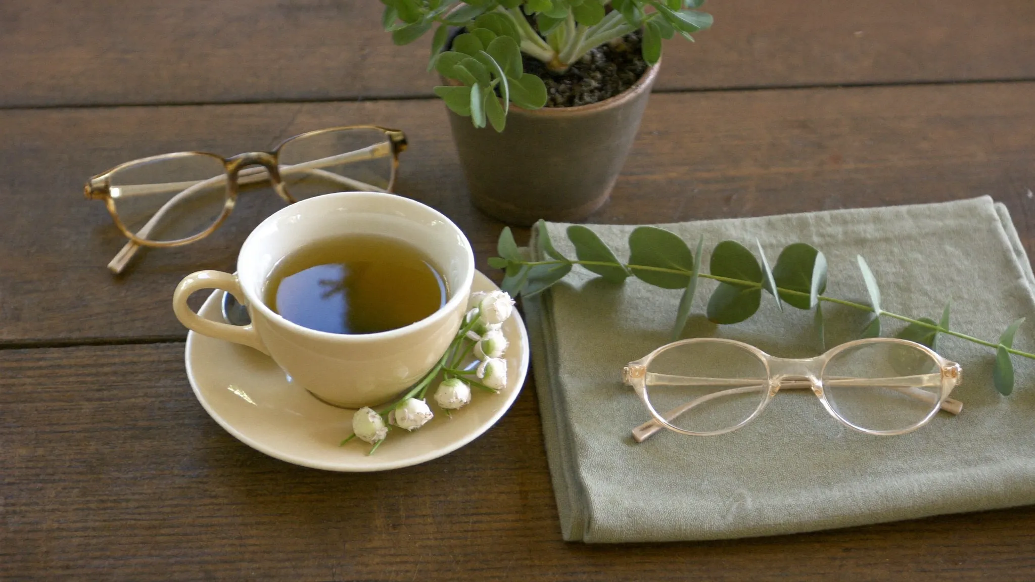 A calm, inviting desk with tea, glasses and flowers