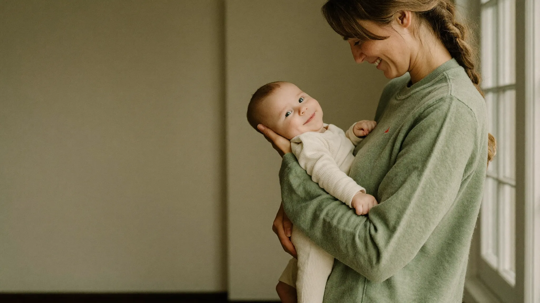 A mother holding her smiling baby at home